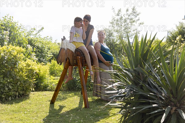 Woman with two girls sitting on a wooden horse