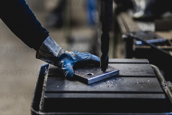 A hole is drilled into a metal plate with a drill