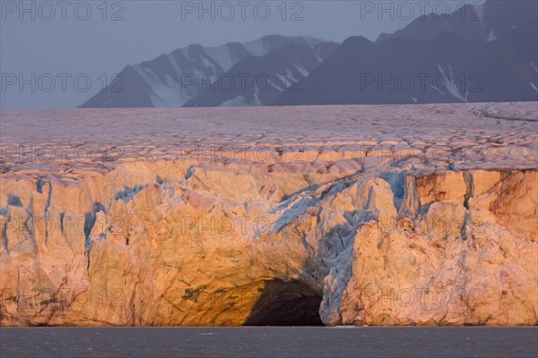 Entrance of giant ice cave at sunset in the Kongsbreen glacier calving into Kongsfjorden