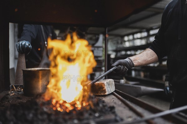 A metalworker works at the forge fire