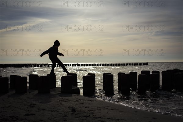 Symbolic photo on the theme of children's courage. A child balances on wooden stilts over the water. Arenshoop