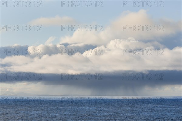 Low-lying rain clouds drift over the open waters of the blue Atlantic Ocean