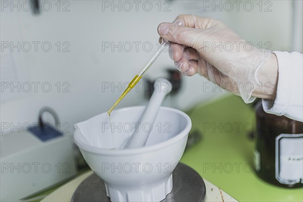 An employee in a pharmacy uses a disposable pipette for virgin olive oil in the prescription
