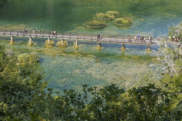 Tourists walking over wooden footbridge over pond in Skradinski buk at the Krka National Park near