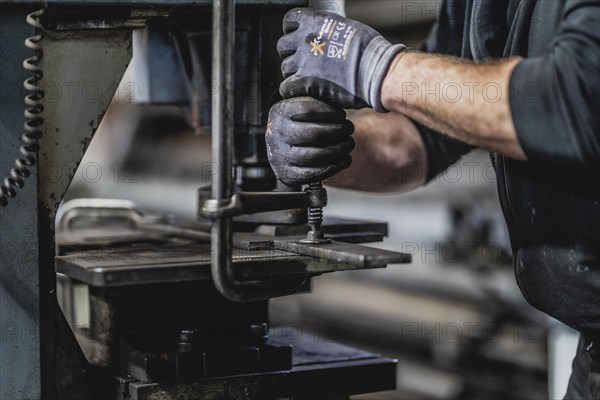 A metal worker clamps a piece of metal into a machine