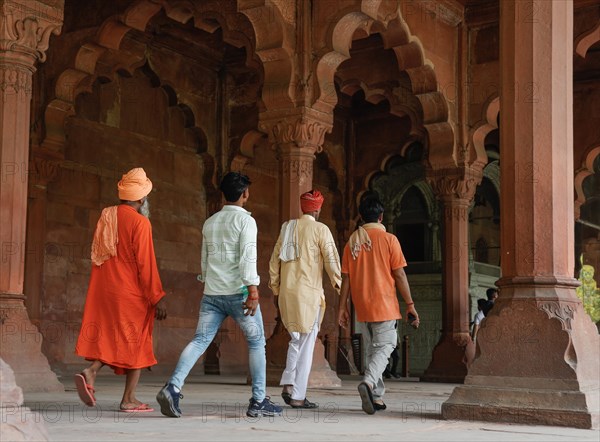 Indian tourists walk through the red sandstone colonnades of the Diwan i Amm in the Red Fort
