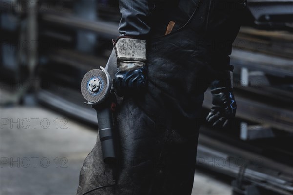 A metal worker carries a cut-off grinder