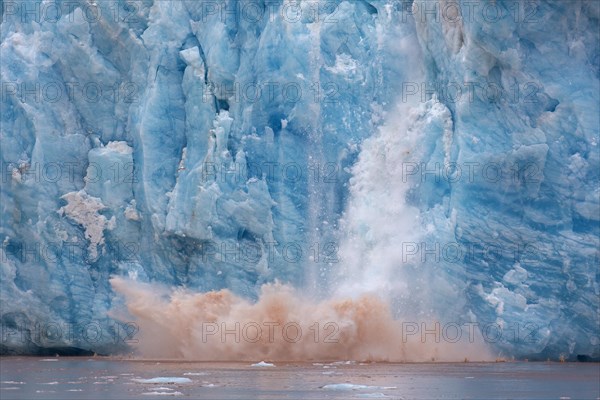 Huge ice chunk breaking from the edge of the Kongsbreen glacier calving into Kongsfjorden