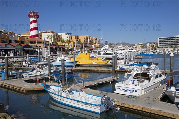 Lighthouse and pleasure boats moored in marina of the port of seaside resort Cabo San Lucas on the peninsula of Baja California Sur