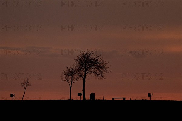 Two walkers silhouetted against the setting sun