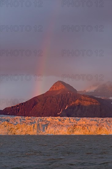 Rainbow over the Kongsbreen glacier in evening light at sunset