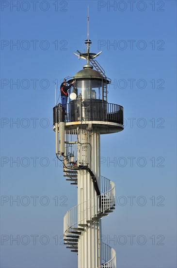 Worker wearing safety harness doing maintenance work on the Alprech lighthouse with spiralling exterior staircase near Le Portel