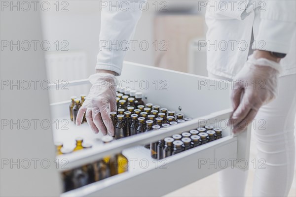 A prescription worker takes a dropper bottle from a drawer