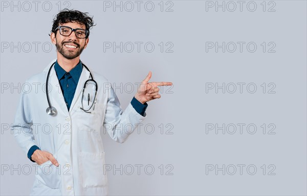 Young doctor pointing a promotion with his finger. Handsome doctor pointing at advertising space isolated. Happy doctor pointing right with finger