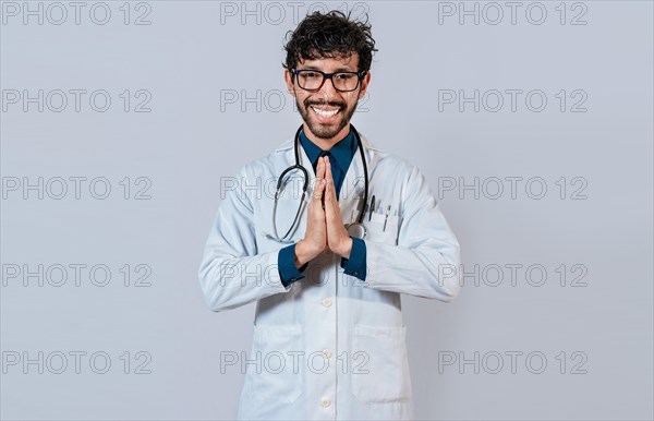 Young doctor with palms together. Smiling doctor putting palms together on isolated background. Handsome doctor with hands together isolated