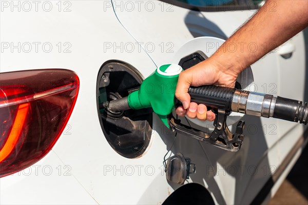 Man with the gun refueling gasoline or diesel fuel in a white car. Concept of transportation