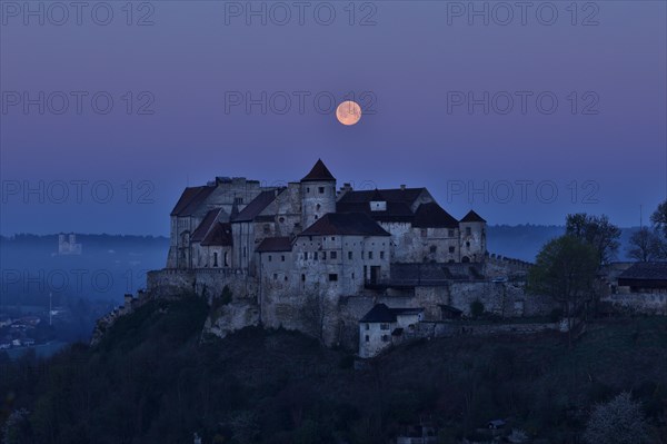 The full moon sets behind the castle in Burghausen