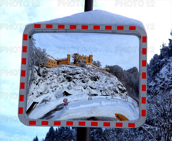 A traffic mirror shows Hohenschwangau Castle in winter