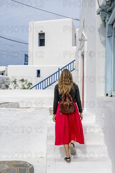 Young woman with red skirt in the alleys of Ano Mera