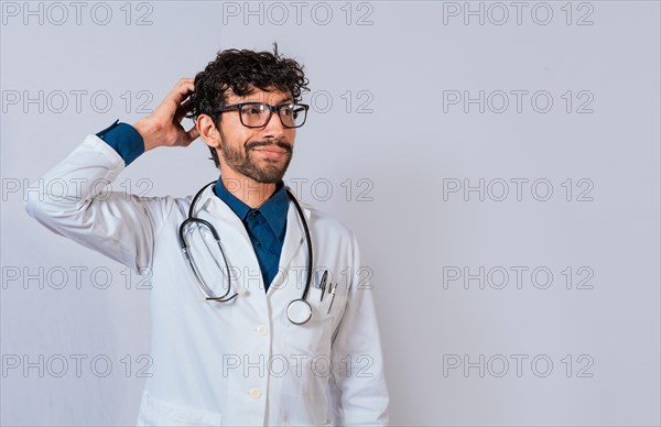 Confused and thoughtful doctor isolated. Male doctor scratching his head isolated. Thoughtful doctor scratching head