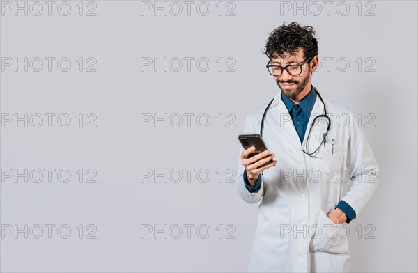 Smiling doctor using cellphone isolated. Young doctor with phone isolated