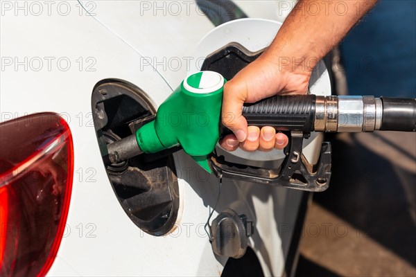 Close-up of a man's hand with the gun refueling gasoline or diesel fuel in a white car. Concept of transportation