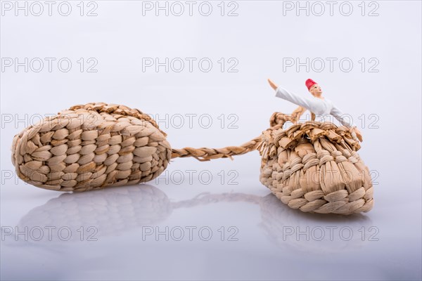 Whirling dervish riding in a straw shoe on a white background