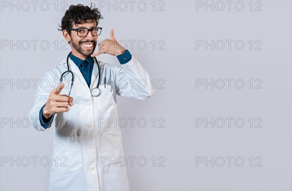 Young doctor making call gesture isolated. Smiling doctor making call gesture and pointing at the camera