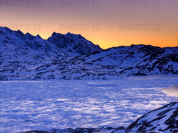 Snowy mountains above the frozen Kong Oscar Fjord at dawn