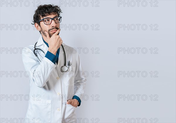 Doctor thinking with hand on chin. Young doctor thinking and looking up isolated