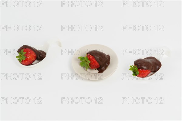 Strawberries with chocolate on a white ceramic spoon isolated on a white background