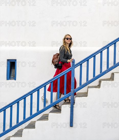 Young woman with red skirt on a staircase with blue banister