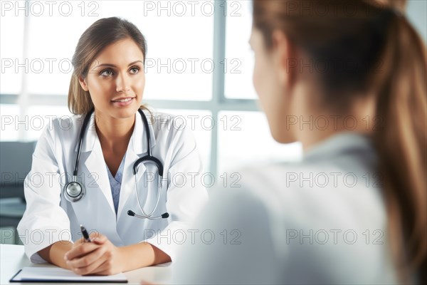 A young female doctor in a white coat with a stethoscope talking to a patient