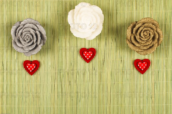 3 decorative roses with 3 small red hearts on a green background