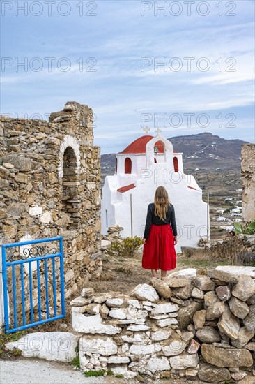 Young woman with red skirt at the entrance gate with ruined wall