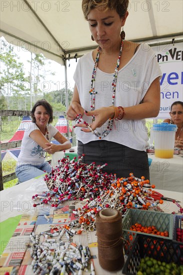 Costa Rican woman checks key rings made from old newspaper