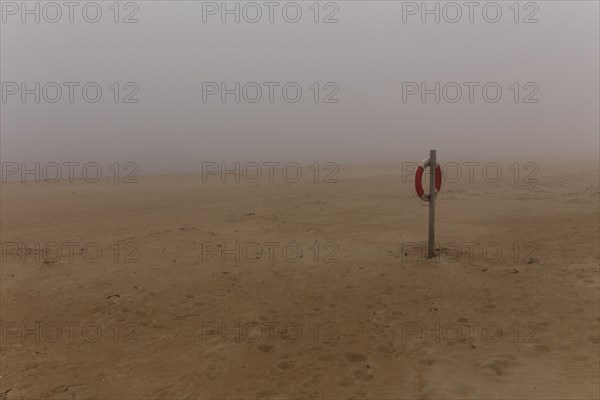 Lifebelt hanging from a post on the beach at Nebel