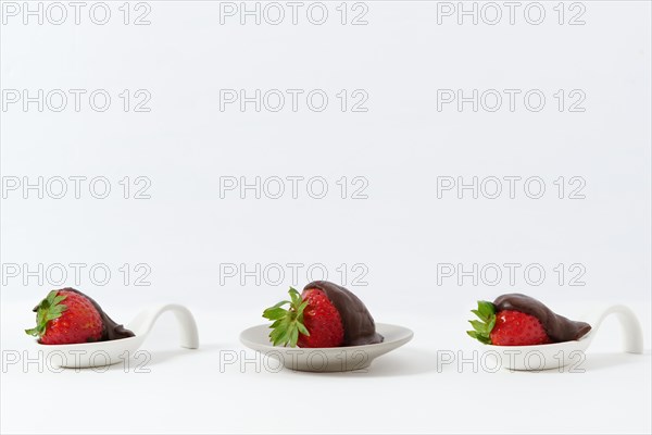 Strawberries with chocolate on a white ceramic spoon isolated on a white background