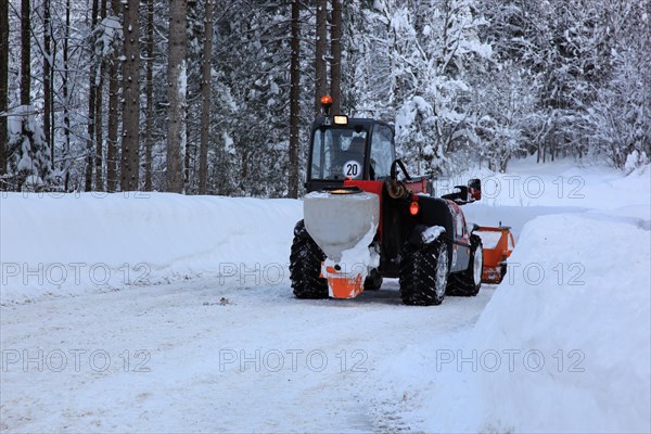 Winter service with snow plough on a country road in Upper Bavaria