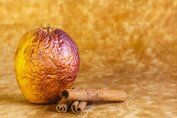 Shrivelled apple with cinnamon sticks