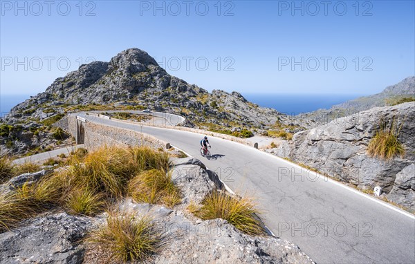 Road cyclists at the mountain pass with serpentines to Sa Colobra