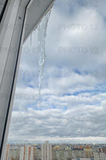 Huge icicle on the roof with a blue sky on background