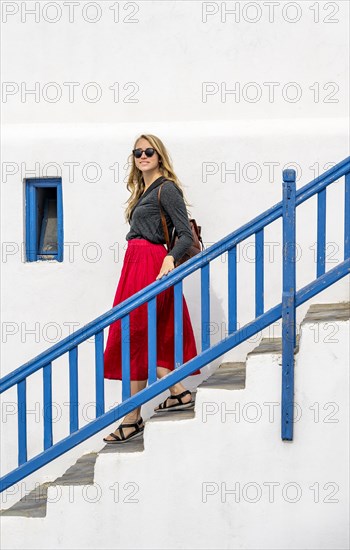 Young woman with red skirt on a staircase with blue banister