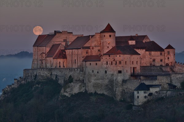 The full moon sets behind the castle in Burghausen