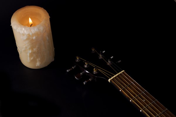 Spanish guitar neck with a candle in the background on a black background