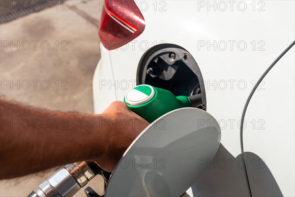 Close-up of a hand with the gun refueling gasoline or diesel fuel in a white car. Concept of transportation
