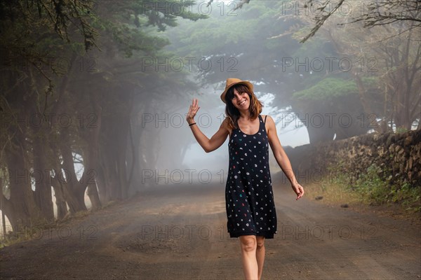 A woman enjoying walking through foggy trees towards the juniper forest in El Hierro. Canary Islands