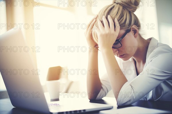 Young woman sitting exhausted at a notebook