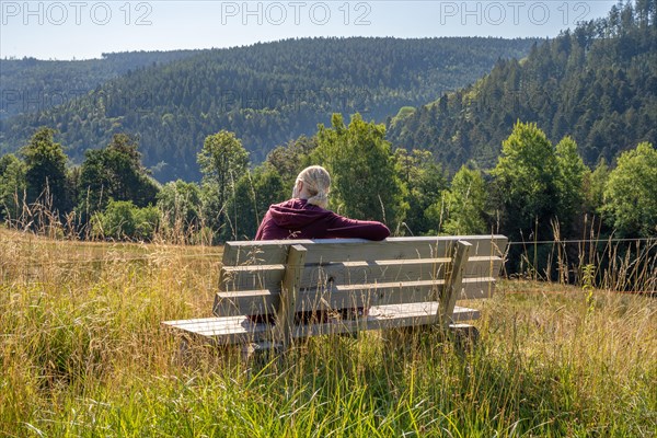 Hiker woman sitting on bench and looking at the woods