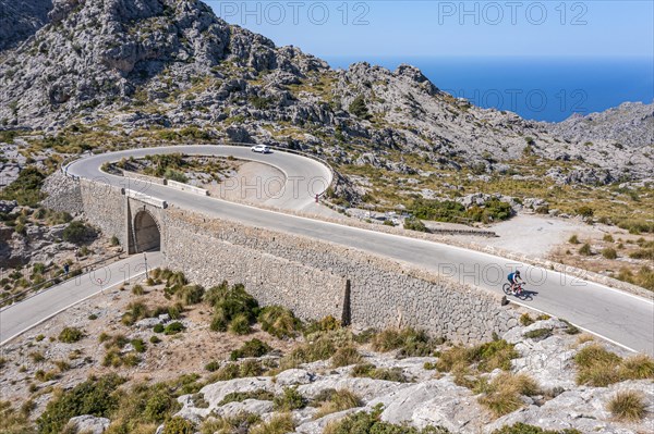 Road cyclists at the mountain pass with serpentines to Sa Colobra